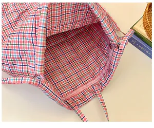 Dettaglio dello zaino a quadretti rosa con coulisse, chiusura a zip e interno spazioso