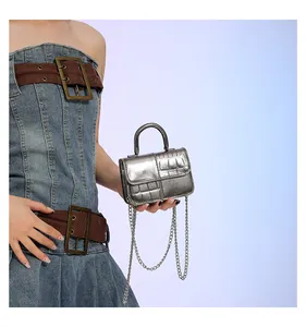 Detail of silver crocodile pattern mini handbag with metallic handle and chain strap
