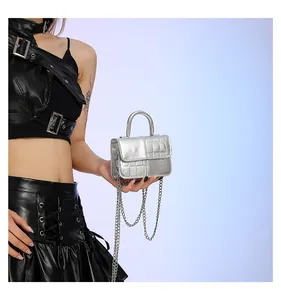 Detail of silver crocodile-embossed mini bag with metallic handle and chain strap
