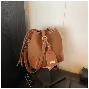 Détail du sac seau marron montrant le mélange de textures daim mat et de finitions cuir verni