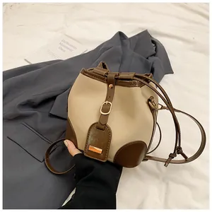 Détail du sac seau bicolore avec fermeture à cordon et sangle à boucle métallique