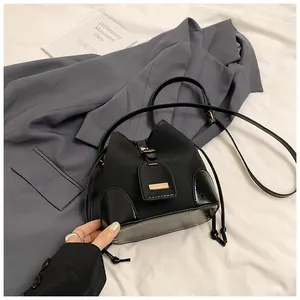 Vue détaillée du sac seau noir avec boucle dorée et bandoulière sur tissu plissé
