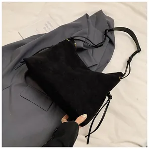 Detail of black matte suede shoulder bag featuring a unique long side knot and slim strap