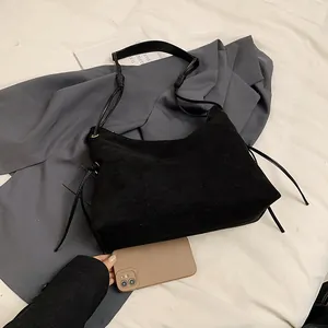 Matte black suede shoulder bag with drawstring detail and adjustable leather strap
