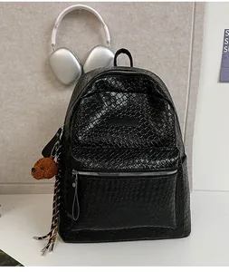 Detail des schwarzen geflochtenen Lederrucksacks mit Textur und süßem Bärenanhänger