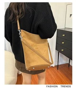 Détail du sac seau en daim fauve avec des clous de protection et une bandoulière fine