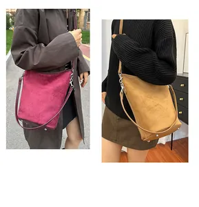 Détail du sac seau en daim avec clous métalliques au fond et bandoulière réglable