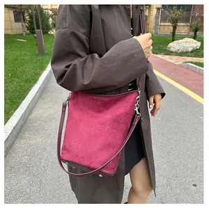 Détail du sac seau en daim bordeaux avec ferrures argentées porté par un mannequin
