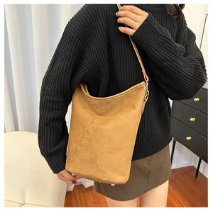 Détail du sac seau en daim marron avec anneaux en métal argenté et surface texturée