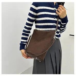 Vue détaillée du sac seau en daim marron foncé avec rivets métalliques et bandoulière