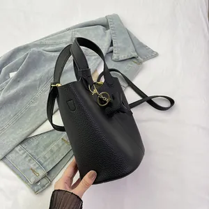 Modische schwarze Beuteltasche aus Leder mit Hundeanhänger auf hellem Denim-Hintergrund