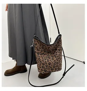 Détail du sac seau à motif léopard avec bordure en cuir noir et bandoulière réglable