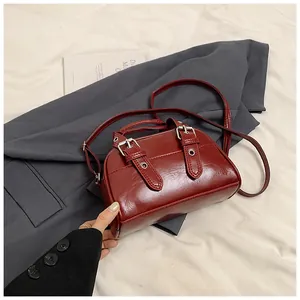 Detail view of burgundy oil-wax leather handbag with adjustable buckles and silver hardware