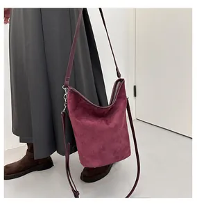 Détail d'un sac seau en daim bordeaux montrant sa texture et sa longue bandoulière