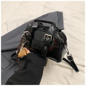 Detail of black glossy leather handbag with silver buckles and waffle charm accessory