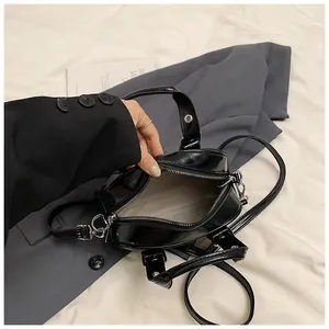Detailed interior of the black glossy shoulder bag with zipper and silver hardware