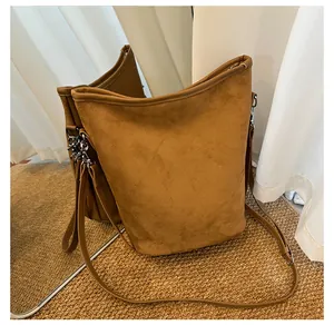 Reflet miroir montrant la texture du sac seau en daim marron et sa bandoulière fine