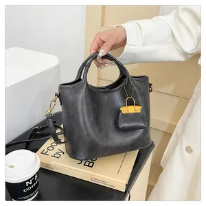 Dettaglio della borsa tote nera opaca con ciondolo mini borsa arancione e anelli D