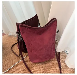Détails d'un sac seau en daim bordeaux avec fermetures éclair et ferrures argentées