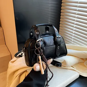 Glossy black leather Boston bag with baseball keychain and adjustable shoulder strap