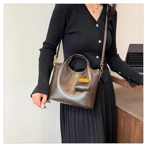Dettaglio di una borsa tote in pelle marrone vintage con mini pochette indossata