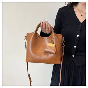 Dettaglio borsa a secchiello vintage in pelle PU marrone con hardware oro e mini pochette