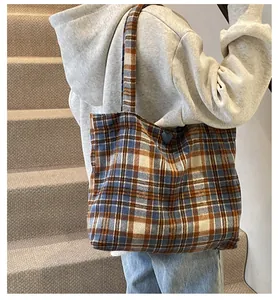 Detail of blue and brown checkered tote bag with blue heart pendant on shoulder strap
