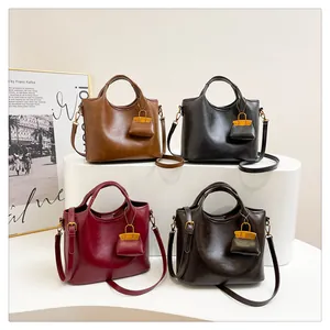 Dettaglio di eleganti borse a secchiello in pelle con mini ciondoli coordinati