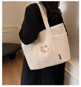 Dettaglio della grande borsa tote in tela con scritte artistiche e tracolla ampia