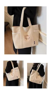 Dettaglio della borsa tote in tela bianco avorio con ricamo rosso e tasca laterale