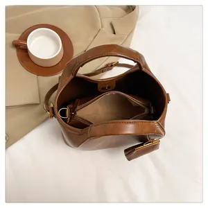 Dettaglio interno della borsa a secchiello marrone scuro con pochette e mini borsa coordinata