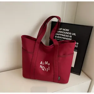 Dettaglio macro della borsa tote in tela bordeaux con tasche laterali e scritte