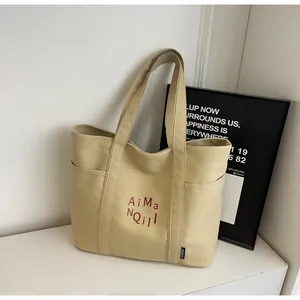 Dettaglio della borsa tote in tela beige con tasca laterale e stampa artistica