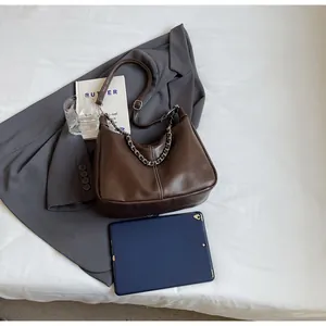 Details einer dunkelbraunen PU-Ledertasche mit weißen Nähten und goldener Metallkette