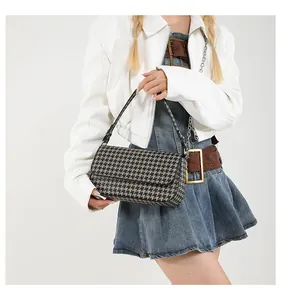 Detail einer schicken Baguette-Tasche mit Hahnentritt-Muster an der Schulter eines Models