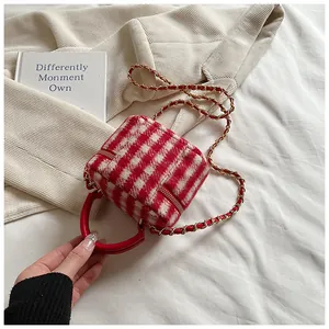 Close-up of red and white plaid tweed mini bucket bag with gold chain and red handle