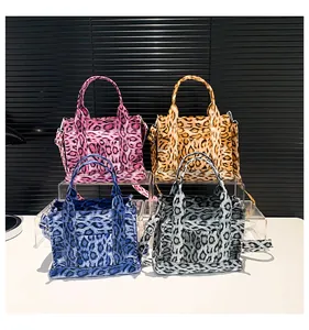 Close-up of leopard print tote bags in pink, brown, blue, and grey with crossbody straps