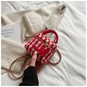 Detail of red and white plaid tweed mini bucket bag with leather handle and gold chain strap