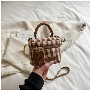 Detail of plaid wool bucket bag featuring dual zippers, leather handle and gold chain strap