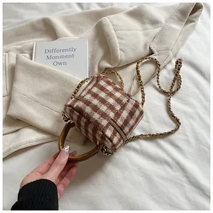 Detail of checkered tweed mini bucket bag with gold chain strap and brown handle