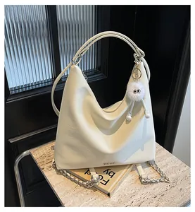 Détail du sac en cuir blanc crème avec chaîne dorée et breloque en peluche douce