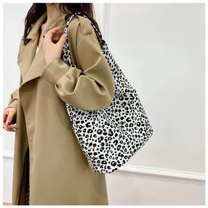 Detailed side view of large leopard print canvas tote bag worn by a model for daily use