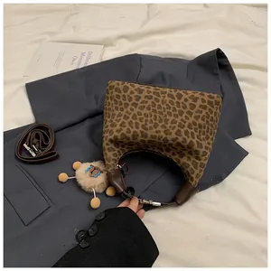 Sac à main léopard avec anse en cuir marron et pendentif en peluche sur un blazer gris
