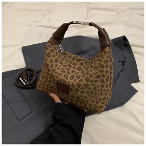 Détail du sac léopard avec patch logo en cuir et bandoulière marron ajustable
