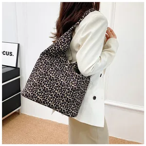Detail shot of a large leopard print canvas tote bag styled as a shoulder bag