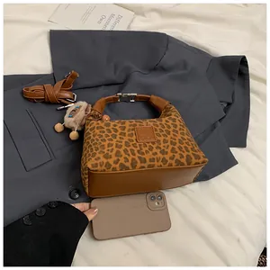 Détail du sac en peluche léopard avec bandoulière en cuir marron et breloque ours