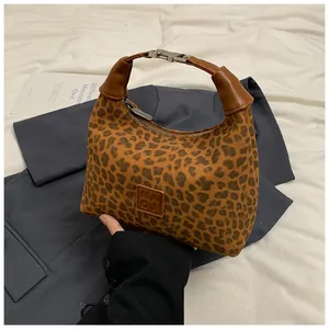 Détail du sac à main léopard avec poignée en cuir marron et fermoir à bouton pression