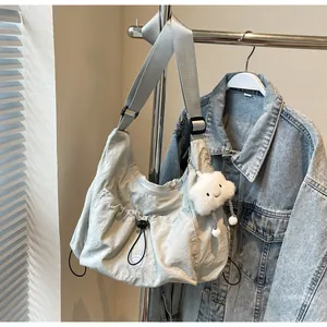 Detail of light grey nylon crossbody bag with drawstring design and plush cloud charm
