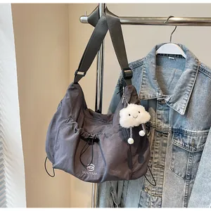 Detail of charcoal grey nylon crossbody bag with logo, drawstring and plush cloud charm