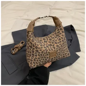 Détail du sac à main imprimé léopard avec poignées en cuir marron et bandoulière réglable